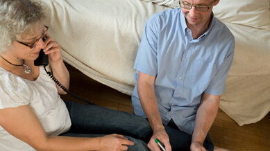 Eltern geben Tipps Erwachsene sitzen auf dem Boden neben dem Bett telefonieren
